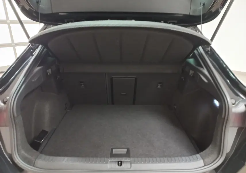 Coffre ouvert vu de l'arrière d'un CUPRA Formentor noir Minuit, montrant un espace de chargement spacieux et éclairé.