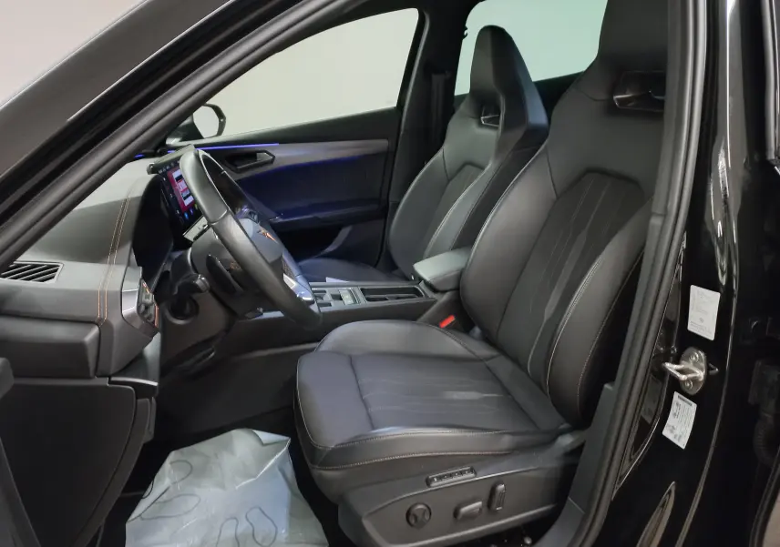 Vue intérieure côté conducteur de la CUPRA Formentor noir minuit, sièges sport en cuir avec éclairage d'ambiance bleu.