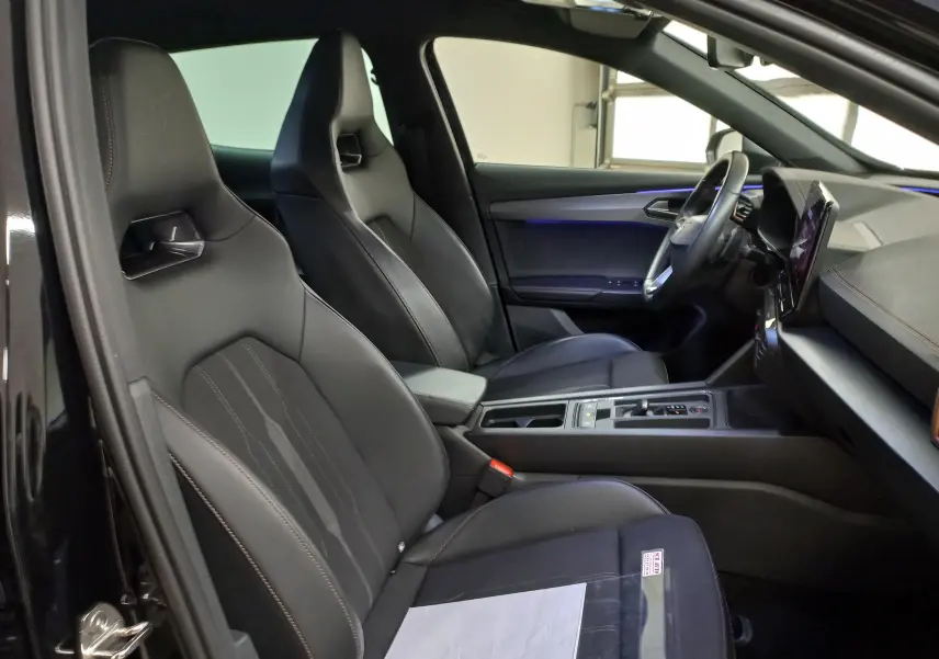 Vue intérieure côté conducteur du CUPRA Formentor noir minuit 2023, sièges sport en cuir avec éclairage d'ambiance bleu.