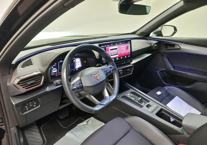 Vue intérieure côté conducteur du CUPRA Formentor 2023 avec éclairage d'ambiance bleu et tableau de bord numérique.