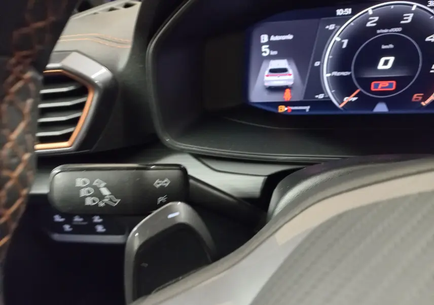 Vue rapprochée du tableau de bord et du volant avec surpiqûres orange du CUPRA Formentor noir Minuit 2023.