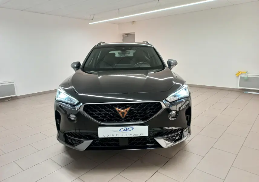 Vue avant frontale du CUPRA Formentor noir minuit avec calandre noire et logo cuivré, éclairage LED allumé en intérieur neutre.