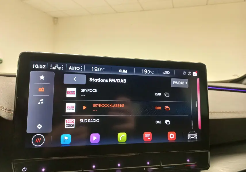 Intérieur du CUPRA Formentor 2023 avec écran tactile central et éclairage d'ambiance violet visible sur le tableau de bord.