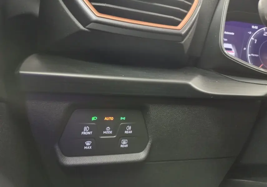 Vue intérieure rapprochée du tableau de bord du CUPRA Formentor 2023 avec éclairage d'ambiance orange et commandes des feux activées.