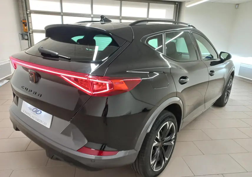 Vue 3/4 arrière droite du CUPRA Formentor noir minuit avec jantes 18'' Performance Black et feux arrière allumés.