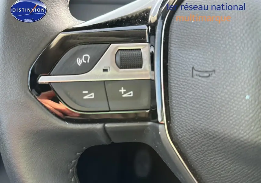 Gros plan sur les commandes multifonctions gauche du volant noir de la Peugeot 208 1.2 PureTech 100 Allure 2024.