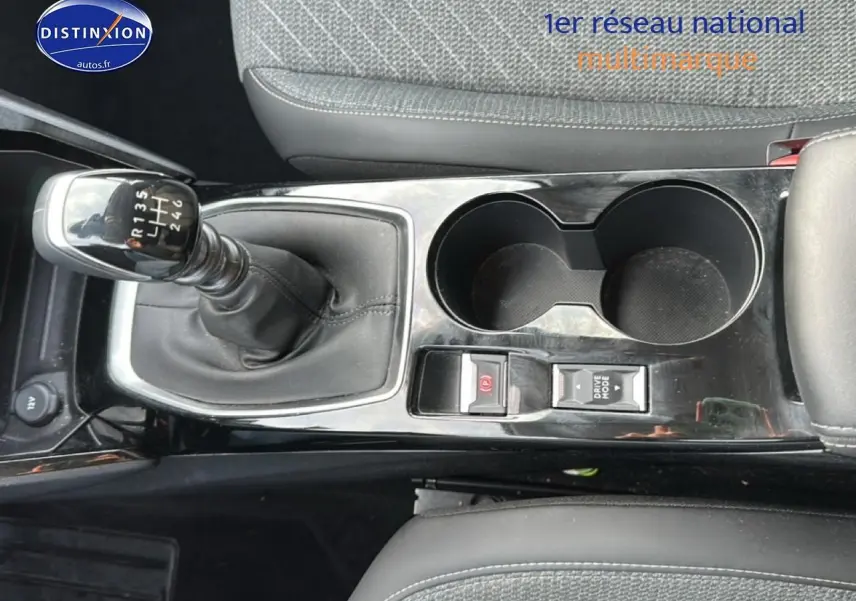 Gros plan sur la console centrale noire de la Peugeot 208 1.2 PureTech 100 Allure avec levier de vitesse manuel et porte-gobelets.
