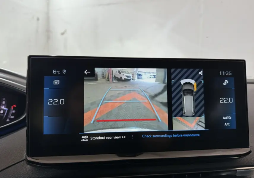 Écran tactile intérieur montrant la caméra de recul et l’aide au stationnement du Peugeot 5008 gris clair, version 2021.