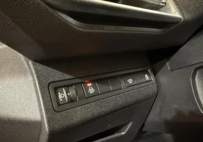 Gros plan sur les commandes noires du tableau de bord côté conducteur du Peugeot 5008 gris clair, avec bouton d’aide au maintien de voie désactivé.