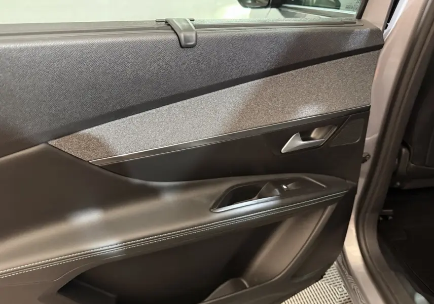 Vue intérieure sur la porte arrière droite du Peugeot 5008 gris clair, avec garniture noire et insert tissu gris.