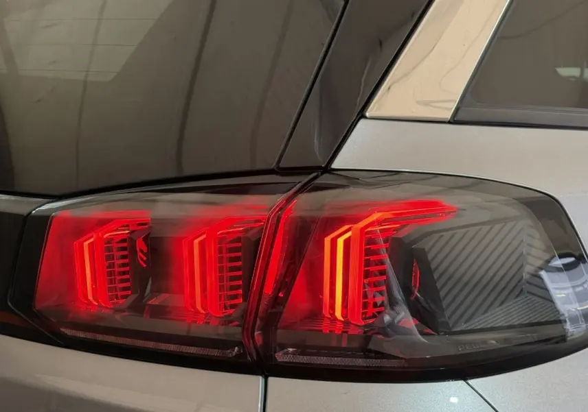 Gros plan sur les feux arrière rouges du côté gauche d’un Peugeot 5008 gris clair, version 2021.