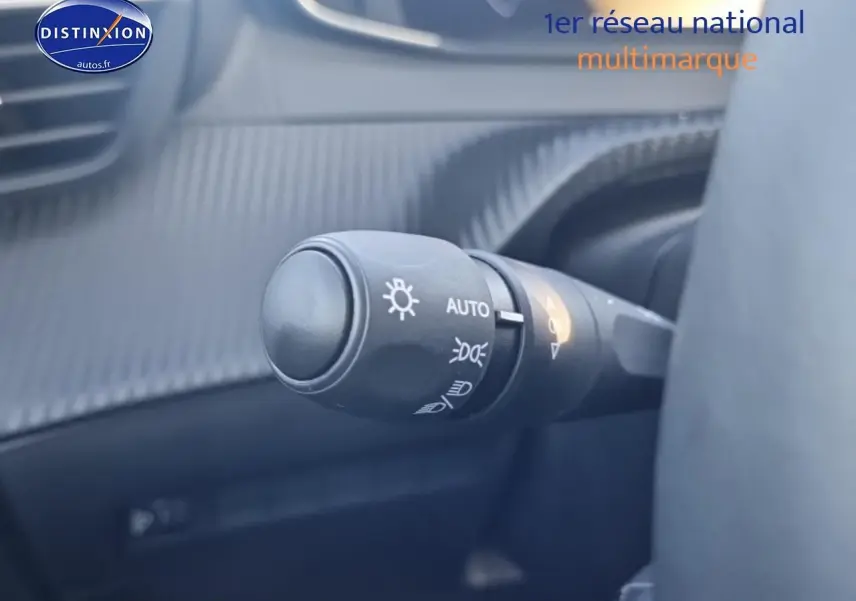 Gros plan sur la commande des phares avec fonction automatique dans l’habitacle gris d’une Peugeot 208 1.2 100 Allure 2025.