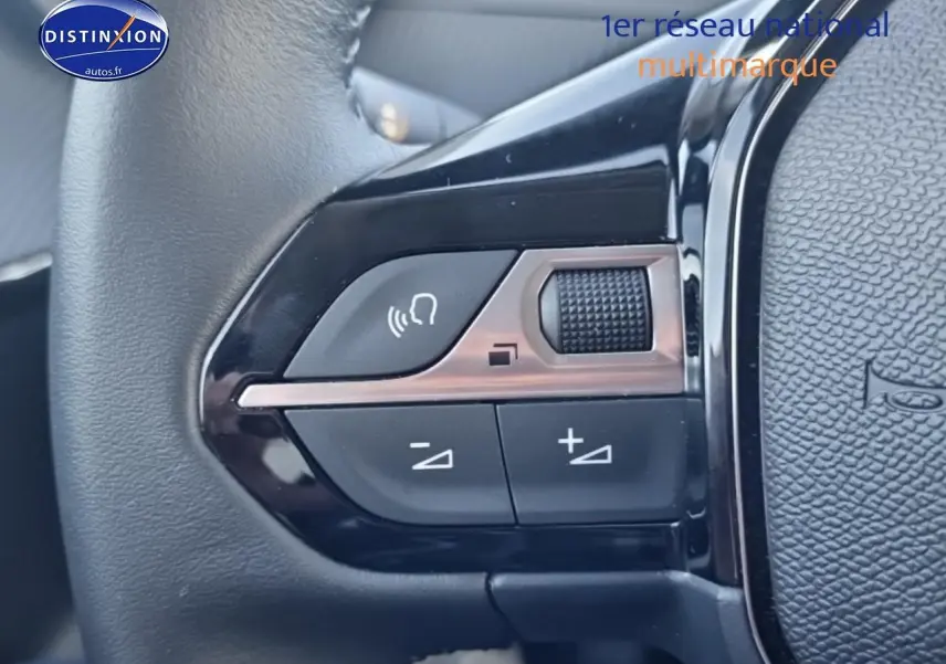 Gros plan sur les commandes audio au volant d'une Peugeot 208 1.2 100 Allure, finition noire brillante.