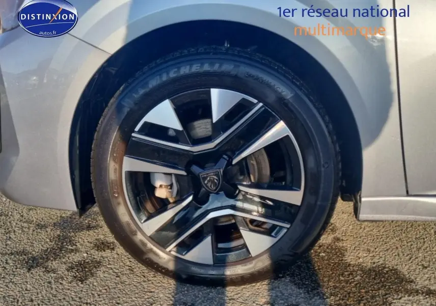 Gros plan sur la roue avant droite gris artense d’une Peugeot 208 1.2 100 allure avec jante alu noire et argent.