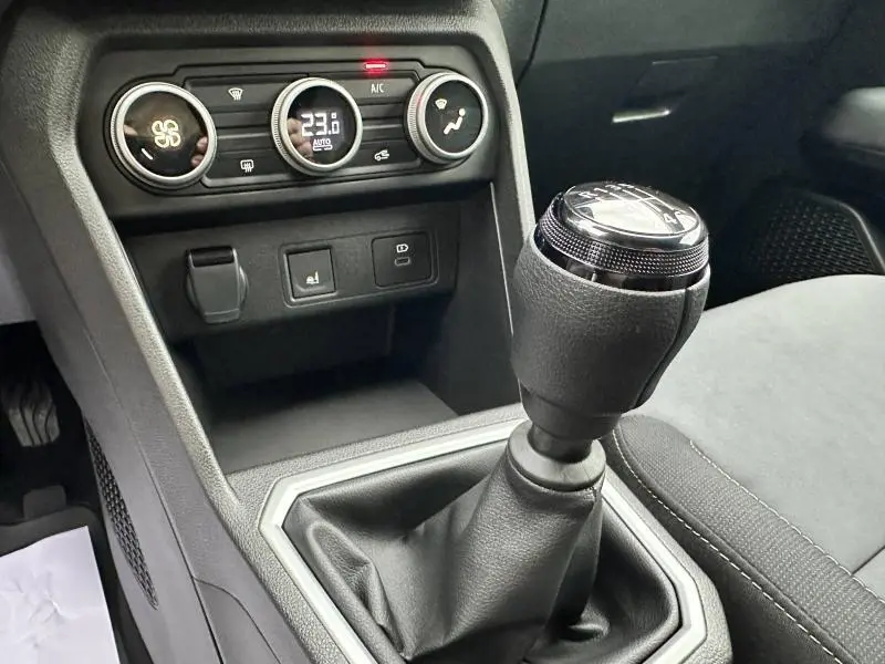 Gros plan sur la console centrale intérieure de la Dacia Jogger 2024, mettant en valeur le levier de vitesses manuel et les commandes de climatisation.