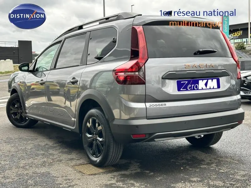 Vue 3/4 arrière droite d'un Dacia Jogger gris schiste métallisé avec jantes noires et barres de toit.