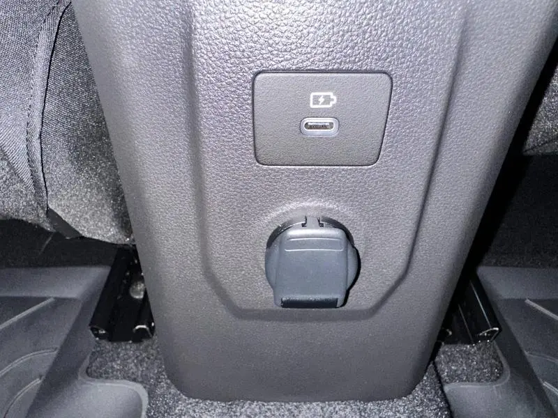 Gros plan sur la console centrale arrière du Dacia Jogger 2024 avec prise USB-C et prise 12V visibles.