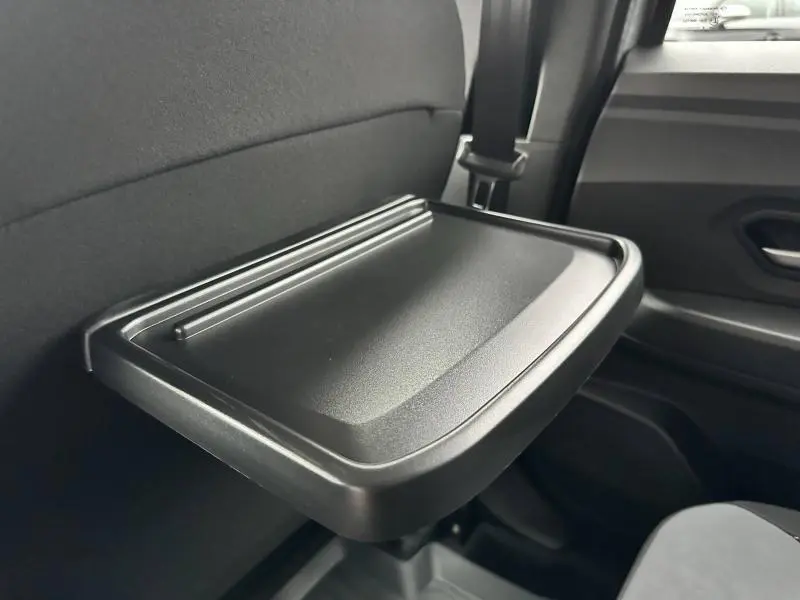 Tablette rabattable noire sur l'arrière du siège avant dans l'habitacle du Dacia Jogger gris Schiste 2024.