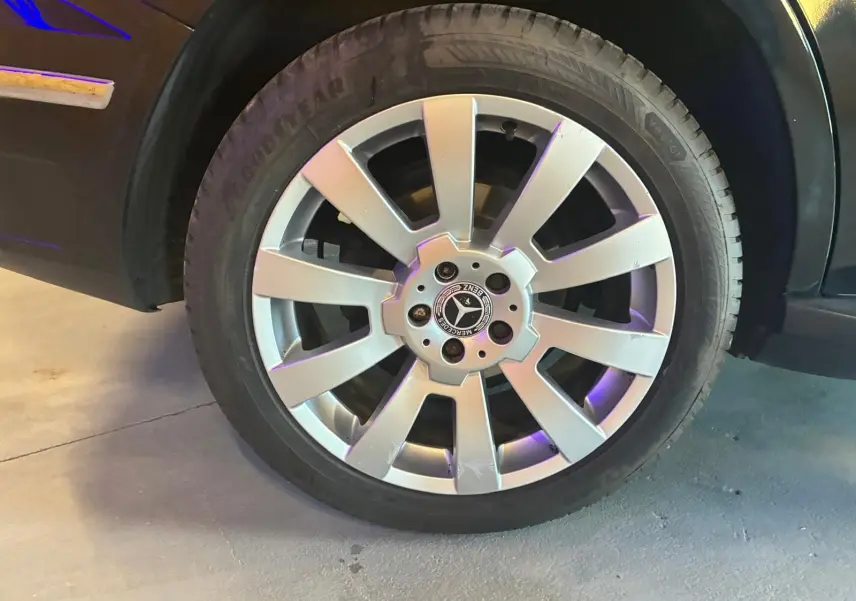 Gros plan sur la roue avant droite d’un Mercedes GLK noir, avec jante argentée à dix branches et logo central visible.