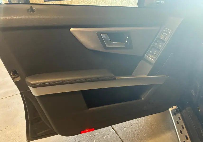 Vue intérieure de la porte avant gauche noire du Mercedes GLK 2012, avec commandes de vitres et poignée argentée.