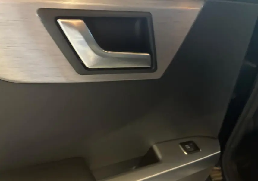 Gros plan sur la poignée intérieure en métal brossé et le panneau de porte noir du Mercedes GLK 220 CDI 2012.