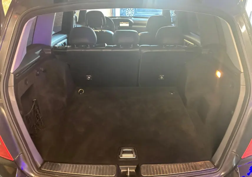 Coffre ouvert vu de l'arrière d'un Mercedes GLK noir, montrant l'espace de chargement et les sièges arrière en cuir noir.