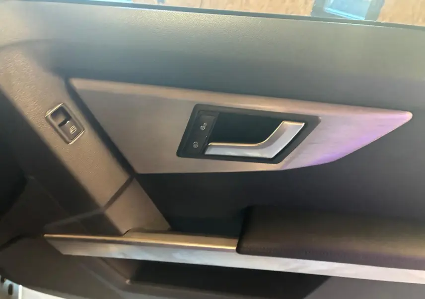 Détail de la poignée de porte intérieure côté gauche du Mercedes GLK noir, avec commande de verrouillage intégrée.