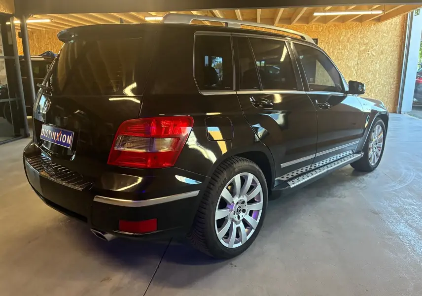 Vue 3/4 arrière droite d’un Mercedes GLK noir 2012 avec jantes alliage et marchepieds métalliques visibles.