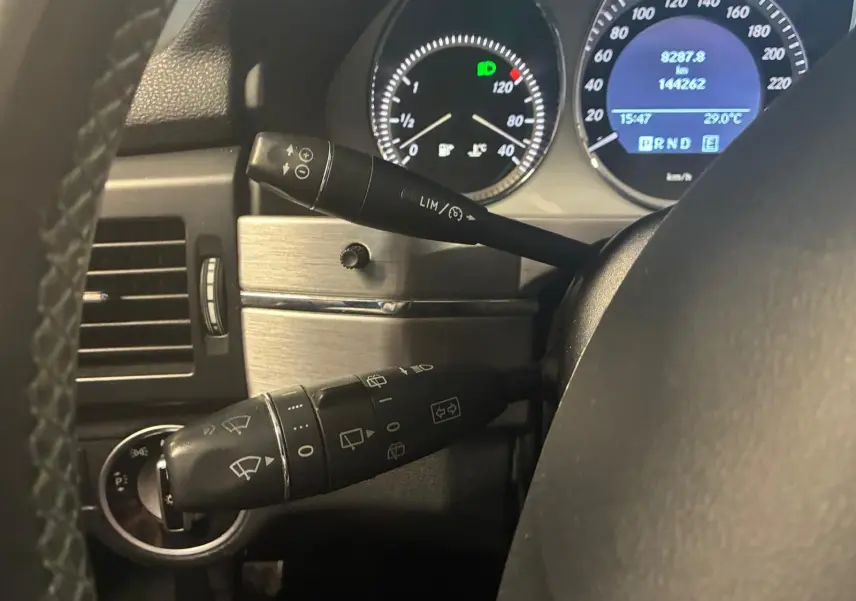Gros plan sur le tableau de bord du Mercedes GLK 2012, montrant les commandes au volant et les compteurs éclairés.