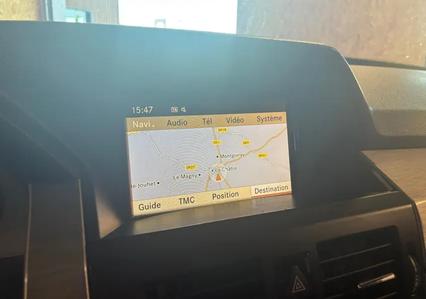 Écran de navigation GPS affichant une carte, situé sur le tableau de bord d’un Mercedes GLK noir, vue intérieure.