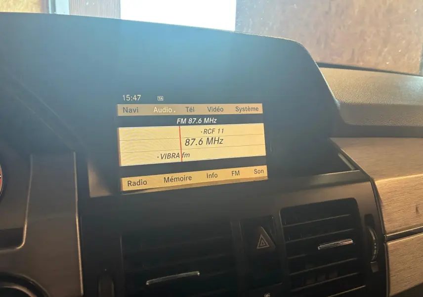Écran central de la Mercedes GLK 220 CDI noir de 2012 affichant la radio FM avec commandes et aérateurs visibles.
