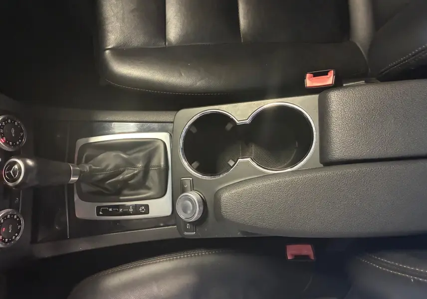 Vue plongeante sur la console centrale noire en cuir du Mercedes GLK 220 CDI avec levier de vitesse automatique et porte-gobelets.
