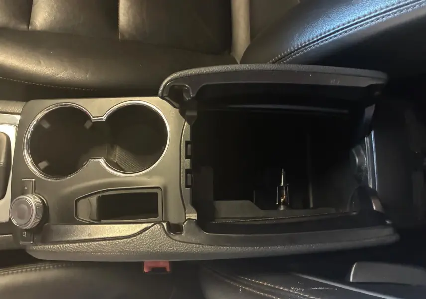 Vue rapprochée de la console centrale ouverte avec porte-gobelets, intérieur cuir noir du Mercedes GLK 220 CDI 2012.