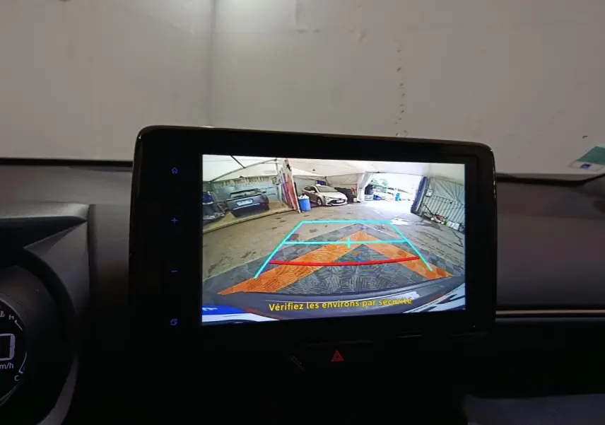 Écran tactile central montrant la caméra de recul avec guidage, intérieur noir du Toyota Yaris Cross gris foncé.