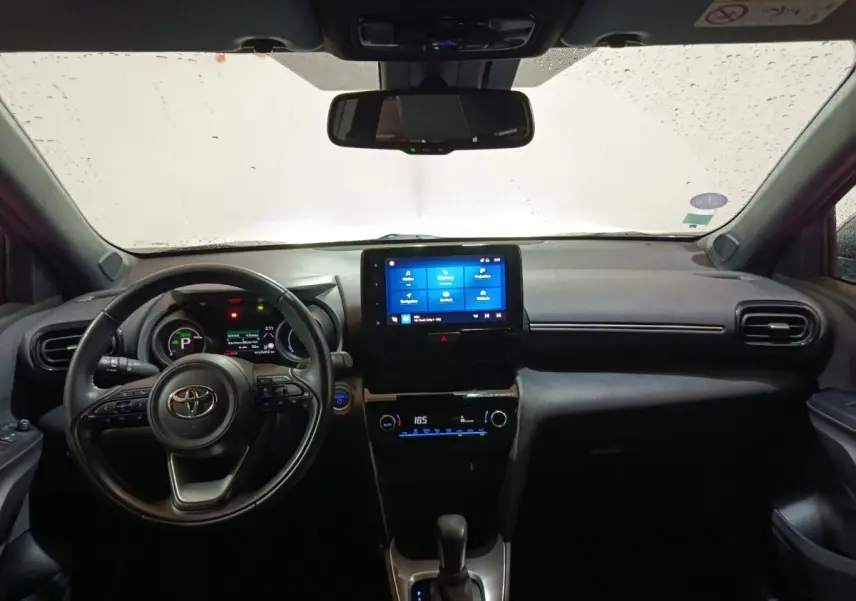 Vue intérieure avant du Toyota Yaris Cross gris foncé 2022, avec tableau de bord numérique et écran tactile central allumé.