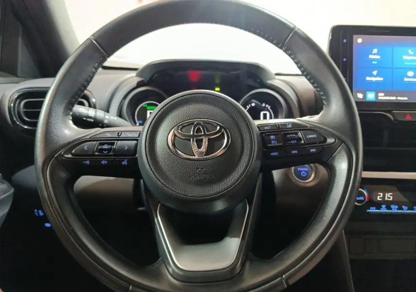 Vue rapprochée du volant cuir noir de la Toyota Yaris Cross 1.5 Hybrid 2022 avec commandes multifonctions et tableau de bord numérique.