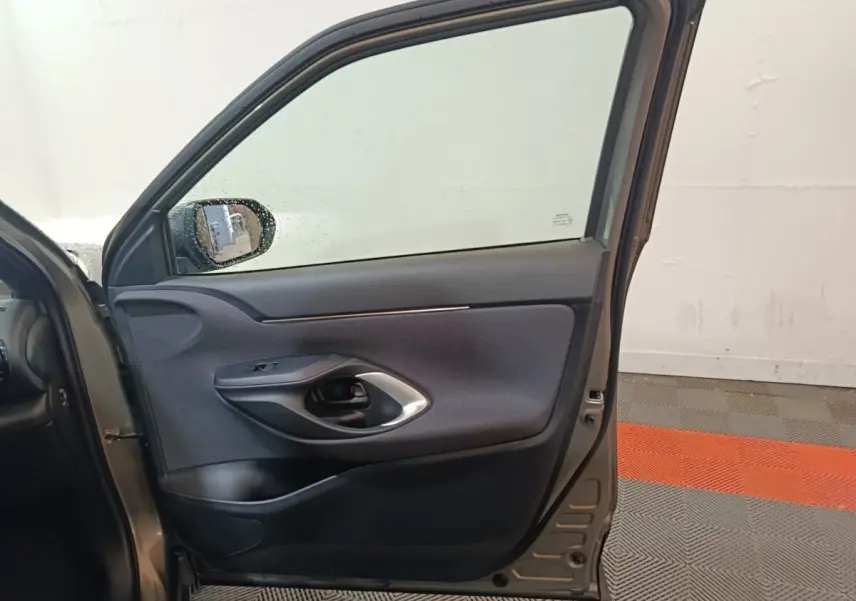Vue intérieure de la porte avant gauche gris foncé de la Toyota Yaris Cross 1.5 Hybrid 2022 avec poignée noire et garniture tissu.