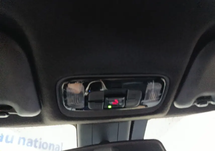 Vue intérieure du plafonnier noir avec commandes d’éclairage et indicateur d’appel d’urgence dans une Toyota Yaris Cross gris foncé.