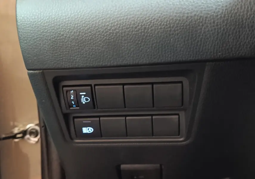 Gros plan sur les commandes d’éclairage à gauche du tableau de bord du Toyota Yaris Cross gris foncé, version hybride 2022.