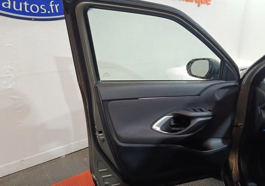 Vue intérieure de la porte avant gauche gris foncé de la Toyota Yaris Cross 2022 avec poignée et commandes de vitres visibles.