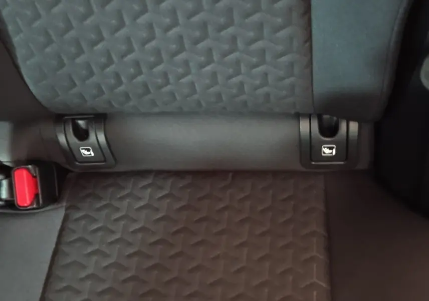 Gros plan sur la banquette arrière grise foncée de la Toyota Yaris Cross 2022, montrant les fixations Isofix et la boucle de ceinture rouge.