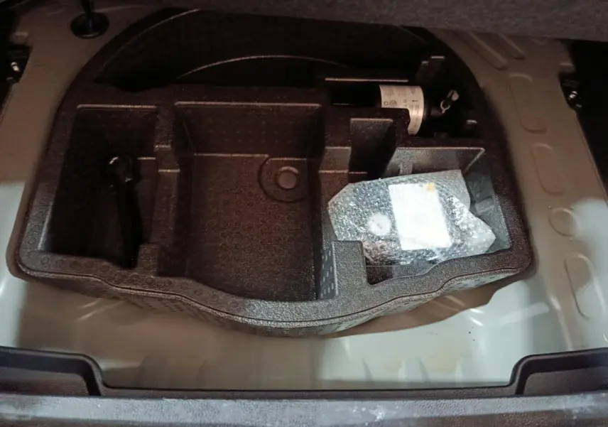 Compartiment de rangement sous le plancher du coffre de la Toyota Yaris Cross 1.5 Hybrid gris foncé, vue plongeante.