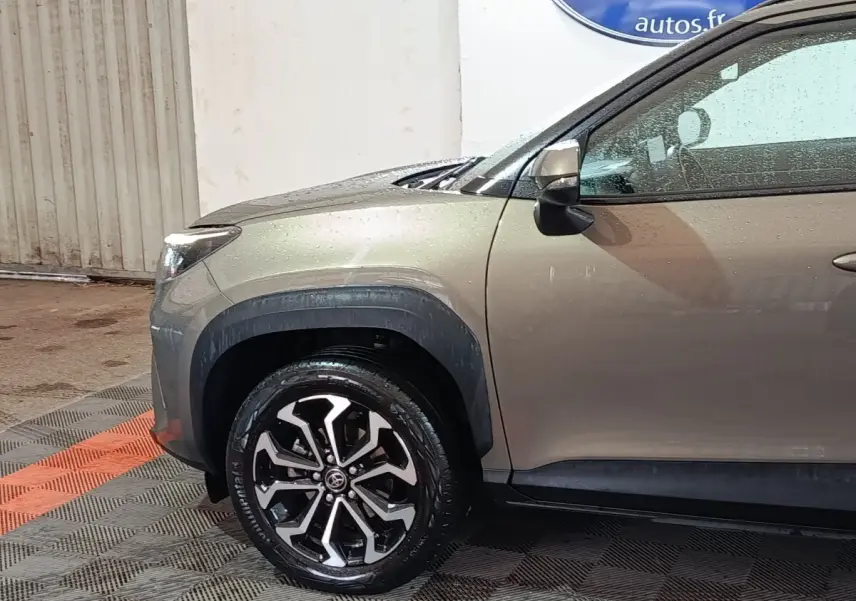 Vue de profil avant droit du Toyota Yaris Cross gris foncé, mettant en valeur la roue alliage et les protections d'ailes noires.