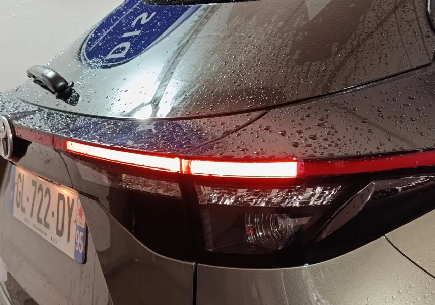 Feu arrière droit allumé d'une Toyota Yaris Cross gris foncé, vue en gros plan sous la pluie.