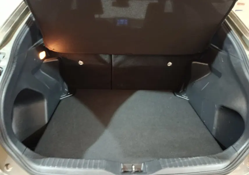 Coffre ouvert de la Toyota Yaris Cross gris foncé, montrant un espace de chargement propre et bien éclairé.