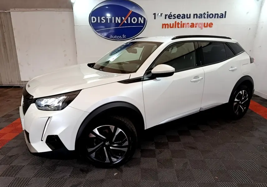 Peugeot 2008 blanc en vue 3/4 avant droit, avec jantes noires et toit noir dans un showroom intérieur.