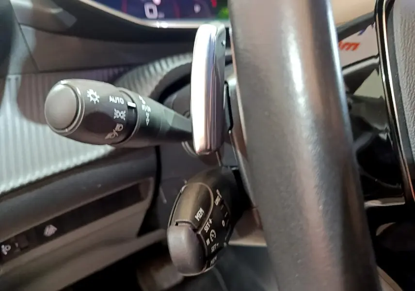 Gros plan sur les commandes au volant en cuir noir du Peugeot 2008, version BlueHDi 130, avec leviers multifonctions.