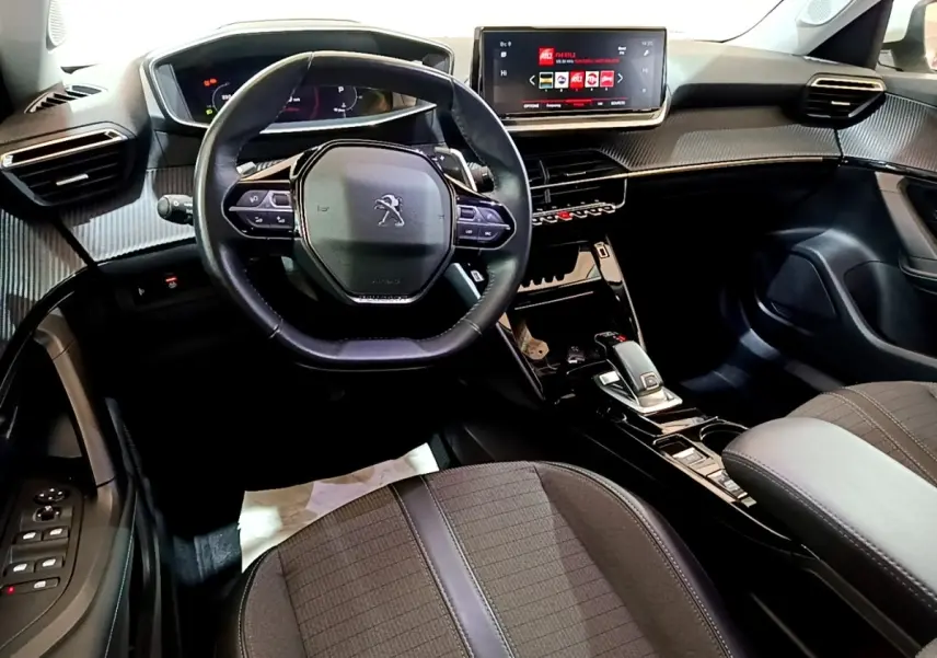 Vue intérieure du poste de conduite du Peugeot 2008 blanc, avec volant cuir multifonctions et écran tactile central.