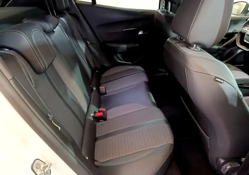 Vue intérieure côté gauche sur la banquette arrière noire du Peugeot 2008 blanc, avec appuie-têtes et ceintures visibles.