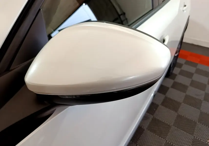 Rétroviseur droit blanc du Peugeot 2008 BlueHDi 130, vue rapprochée avec carrosserie et sol damier en arrière-plan.